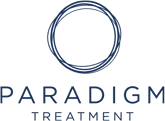 Logo for Paradigm Treatment featuring a dark blue, hand-drawn style circular emblem above the text in capital letters.