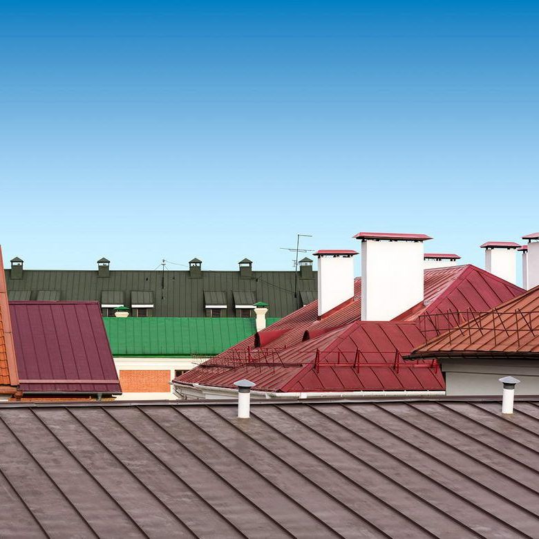 Red and brown rooftops with chimneys under a clear blue sky