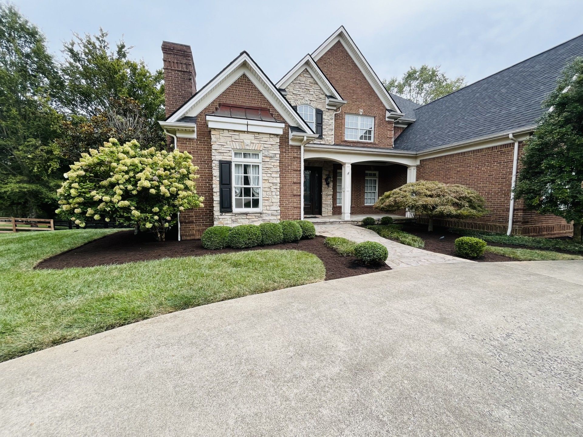 A large brick house with a large driveway in front of it