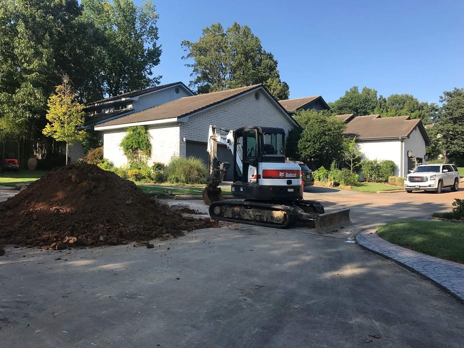 Mini Excavator on a Driveway Next to a Pile of Dirt