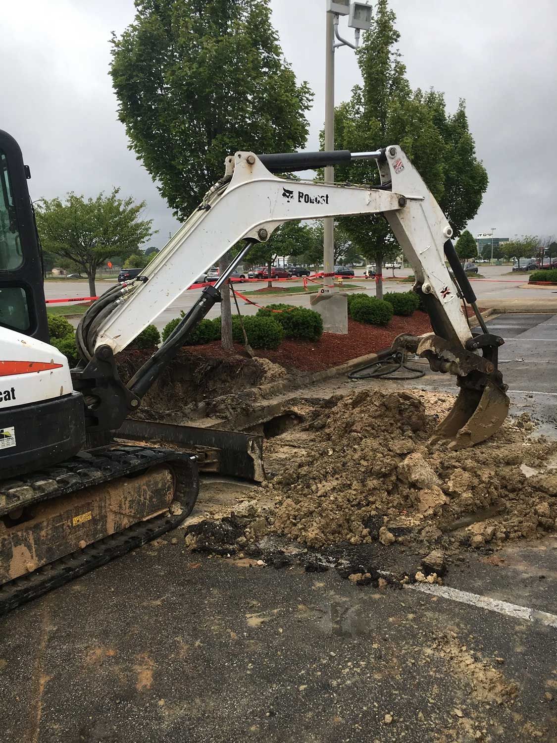 A Small Excavator Digging in a Parking Lot