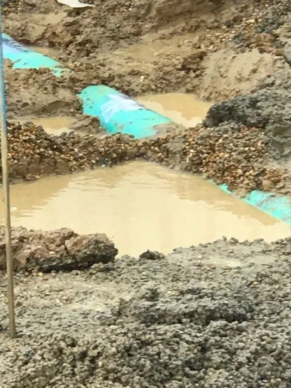 A Trench Filled with Muddy Water and Blue Pipe