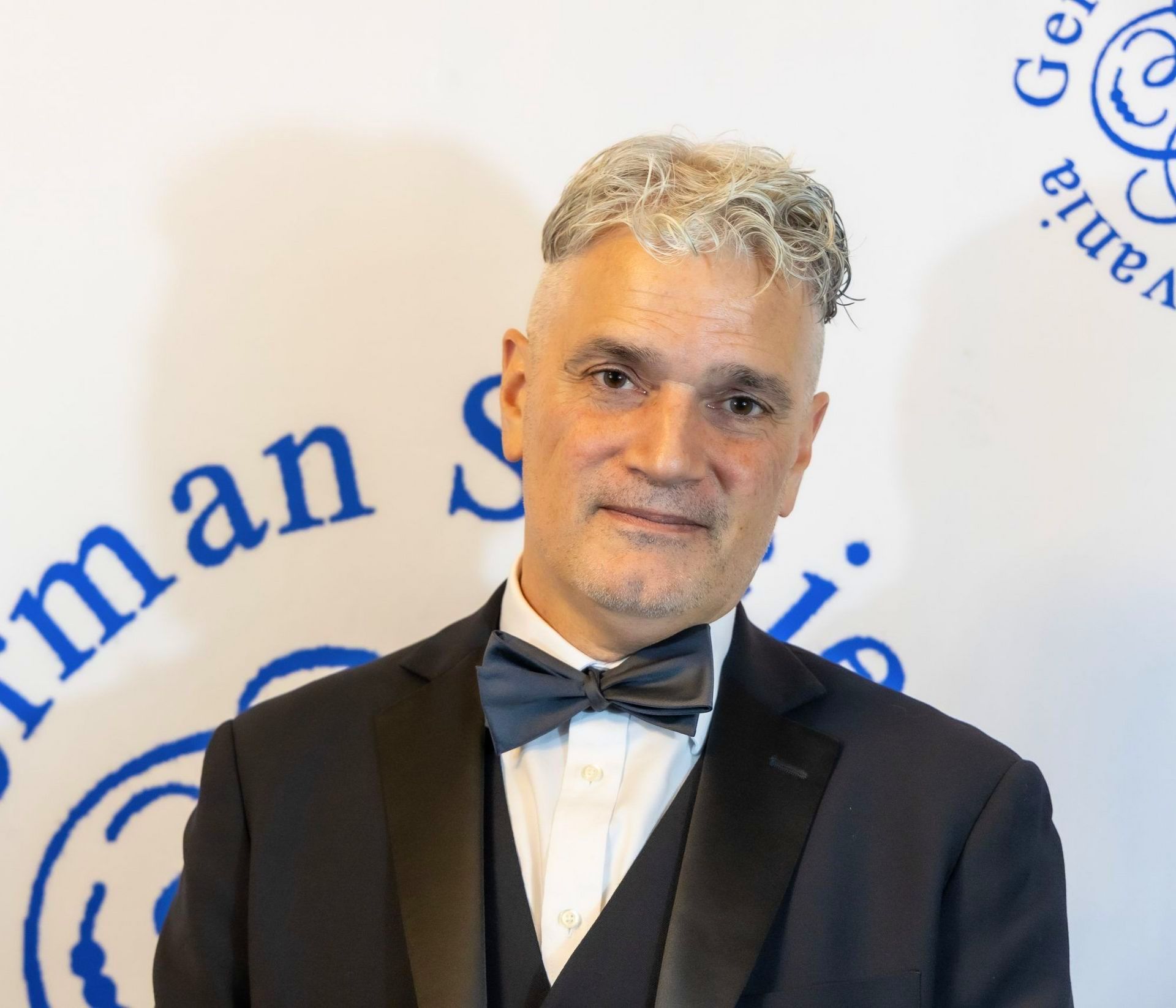 A man in a tuxedo and bow tie is posing for a picture.