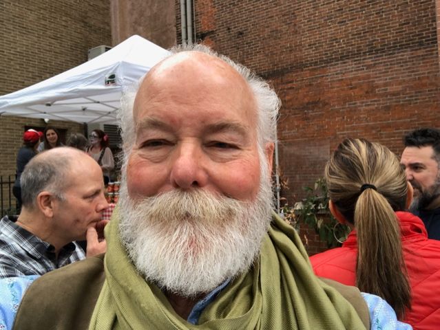 A man with a beard and scarf is smiling for the camera.