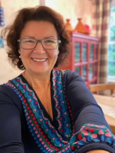 A woman wearing glasses and a blue shirt smiles for the camera