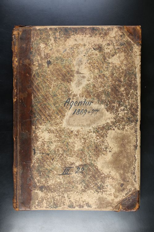 An old book is sitting on a table with a black background.