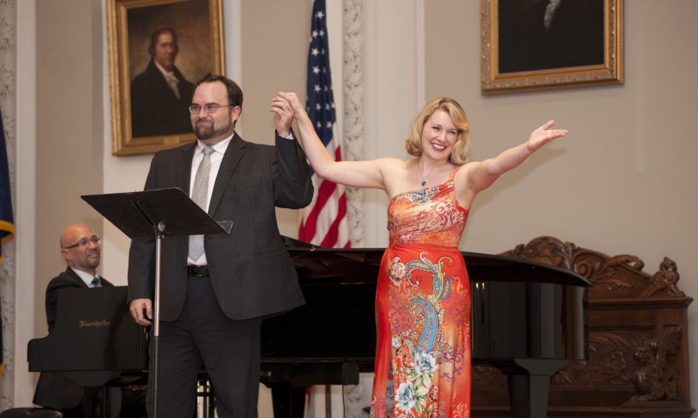 A man and a woman are holding hands in front of a piano.