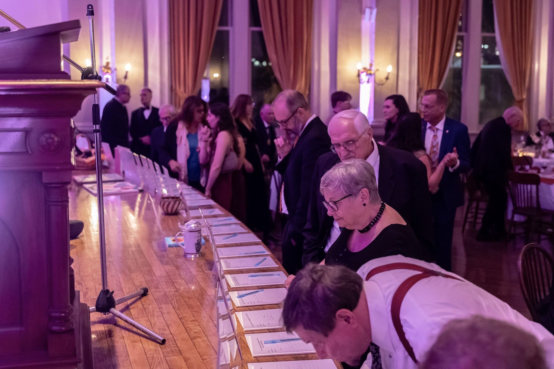 A group of people are standing around a long table in a room.