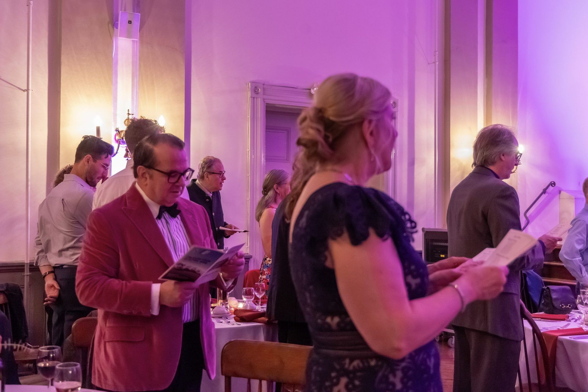 A group of people are standing in a room with purple lights.