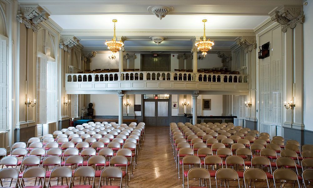 A large auditorium with rows of chairs and a balcony