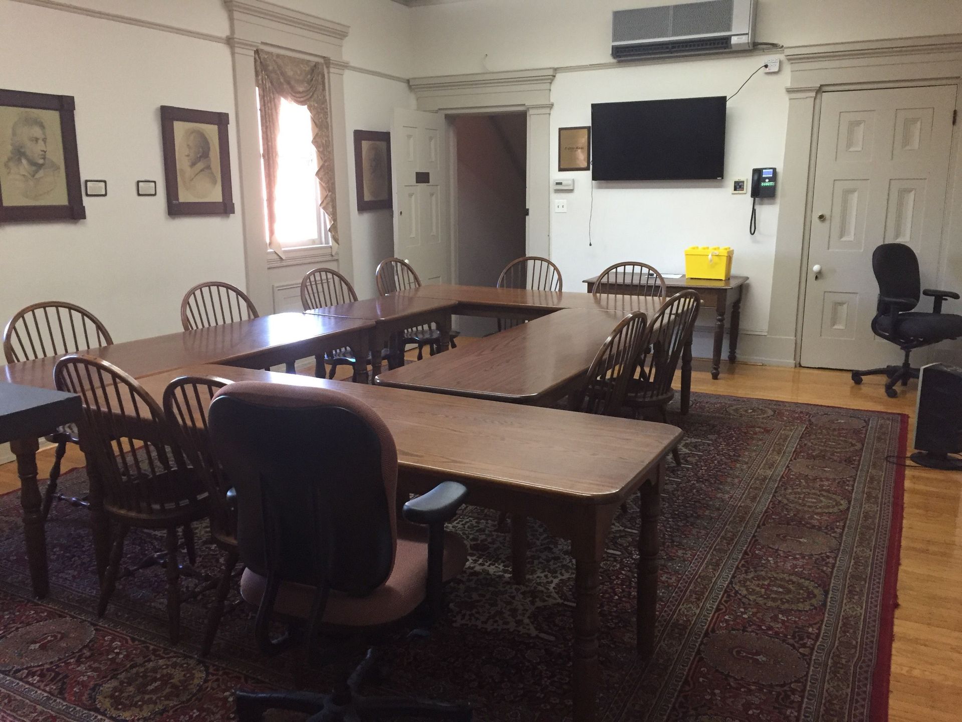A room with tables and chairs and a television on the wall