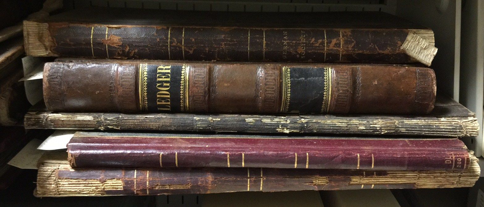 A stack of old books on a shelf including one called a tiger