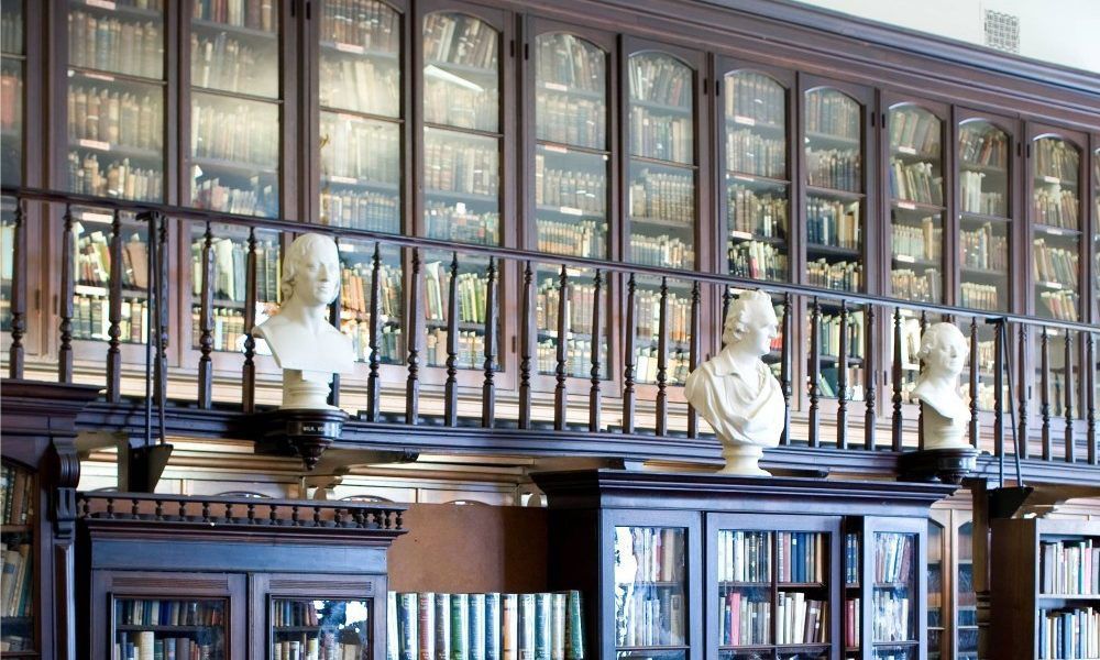 A library with lots of books and busts on the shelf