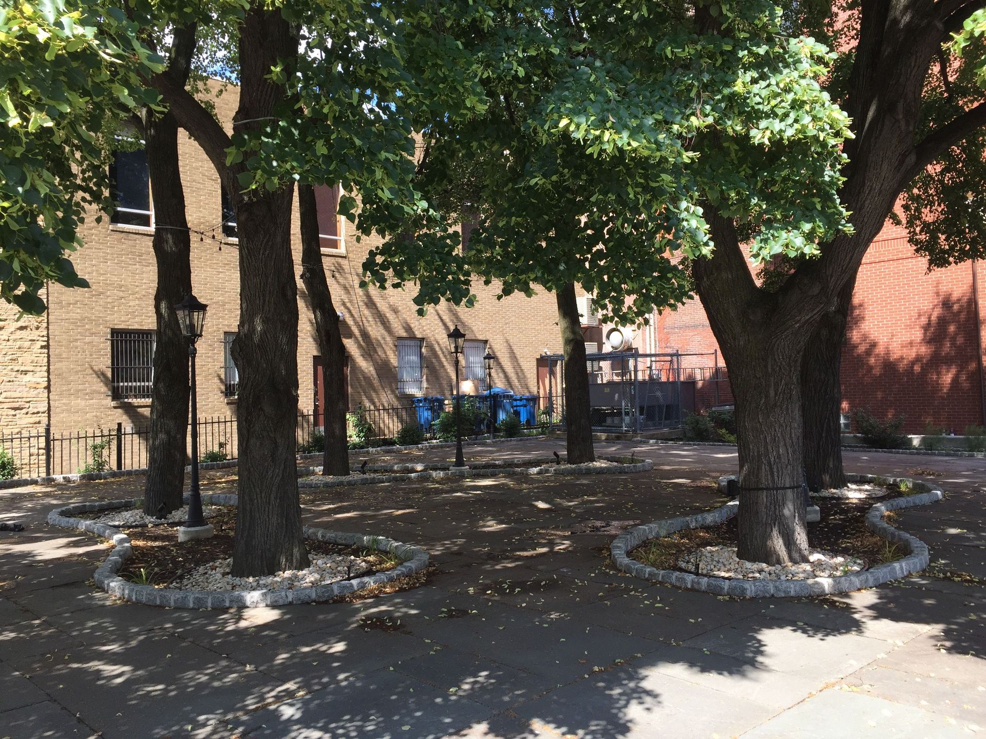 A park with trees and a brick building in the background