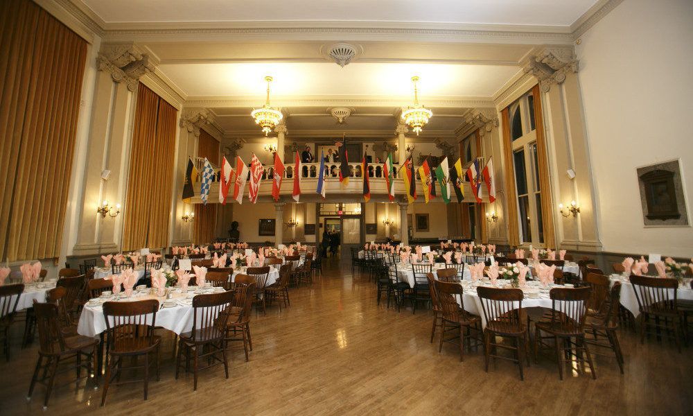 A large room with tables and chairs and flags hanging from the ceiling