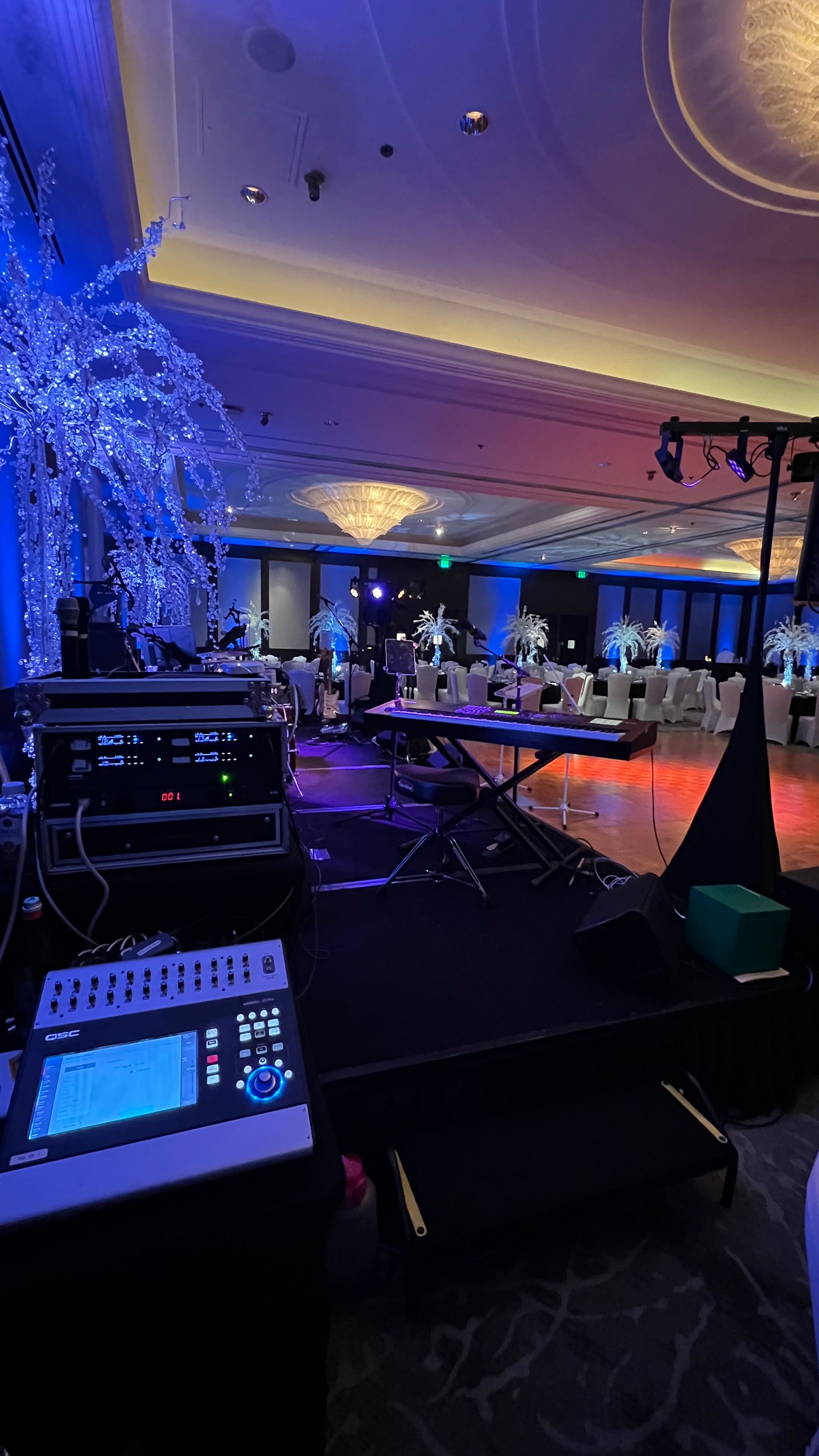 Stage setup in a ballroom with lighting, audio equipment, and decorated tables.