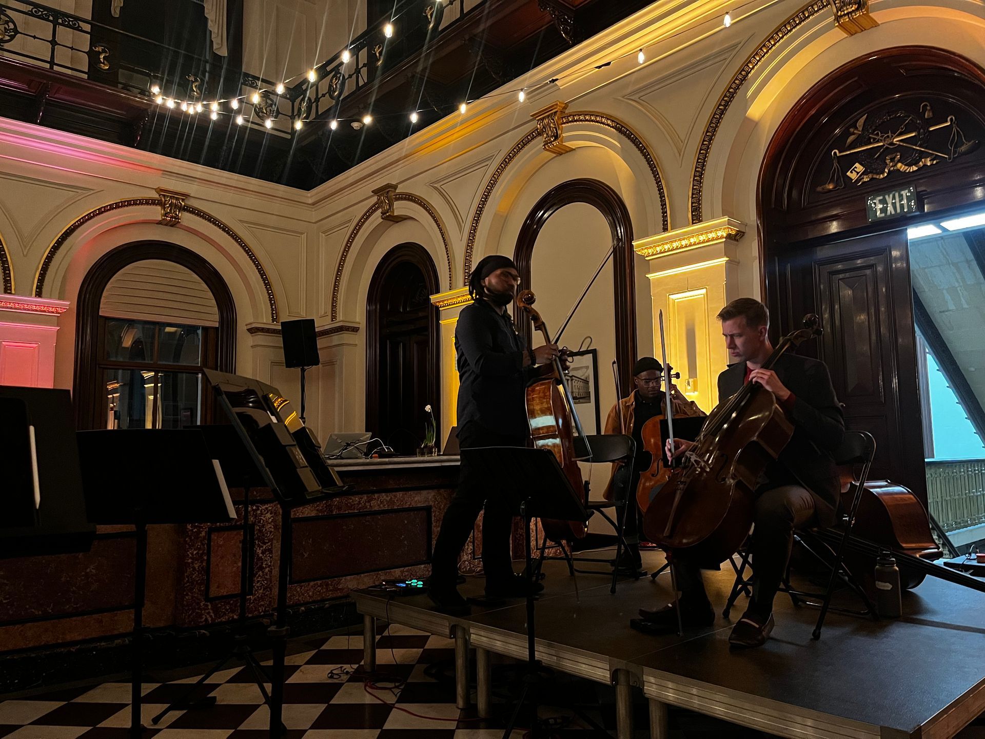 String quartet performing on stage in a grand hall, bathed in warm lighting.