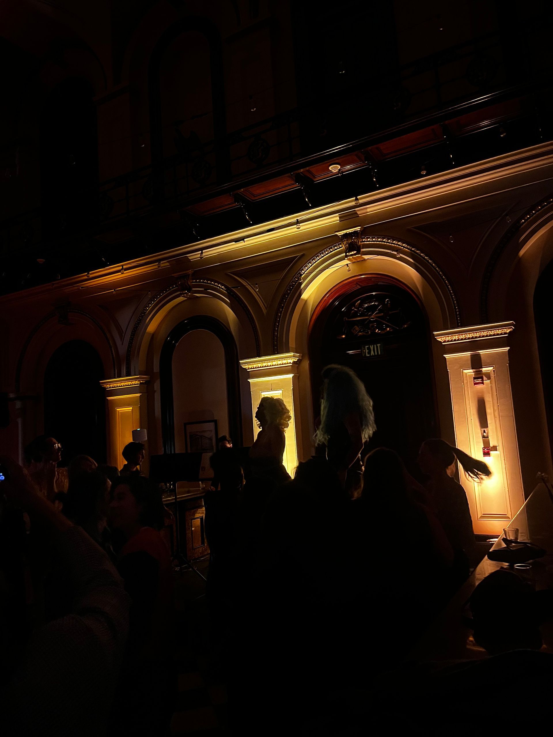 People silhouetted in front of ornate arches lit in gold, likely at a formal event.