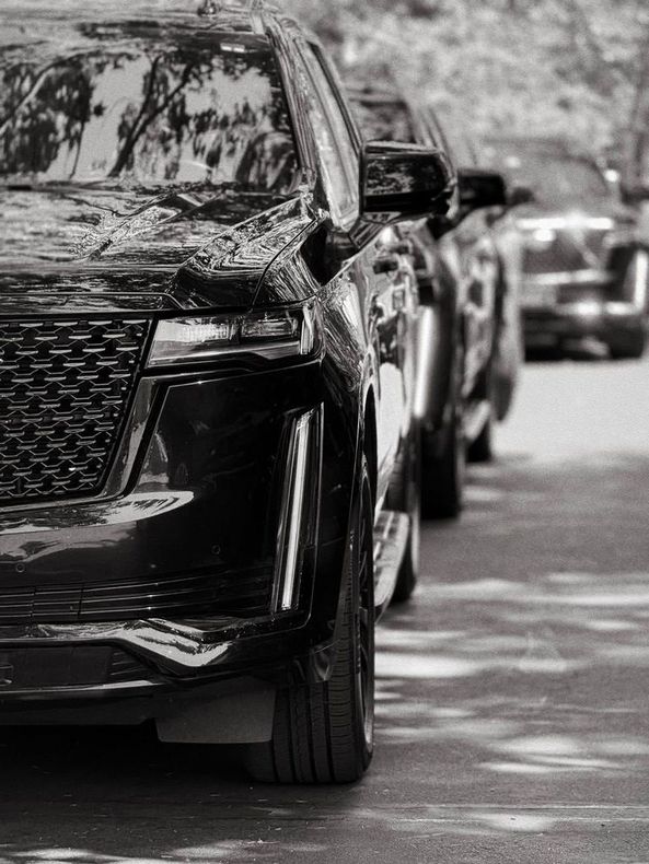 A black and white photo of a row of cars parked in a parking lot.