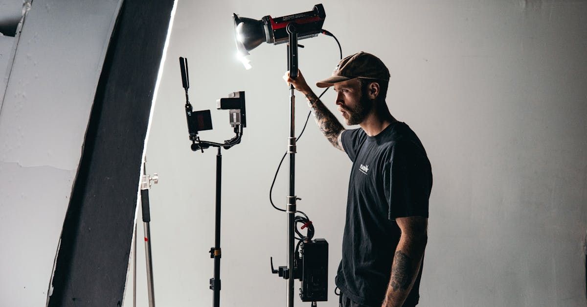 A man is standing in front of a camera in a studio holding a light.