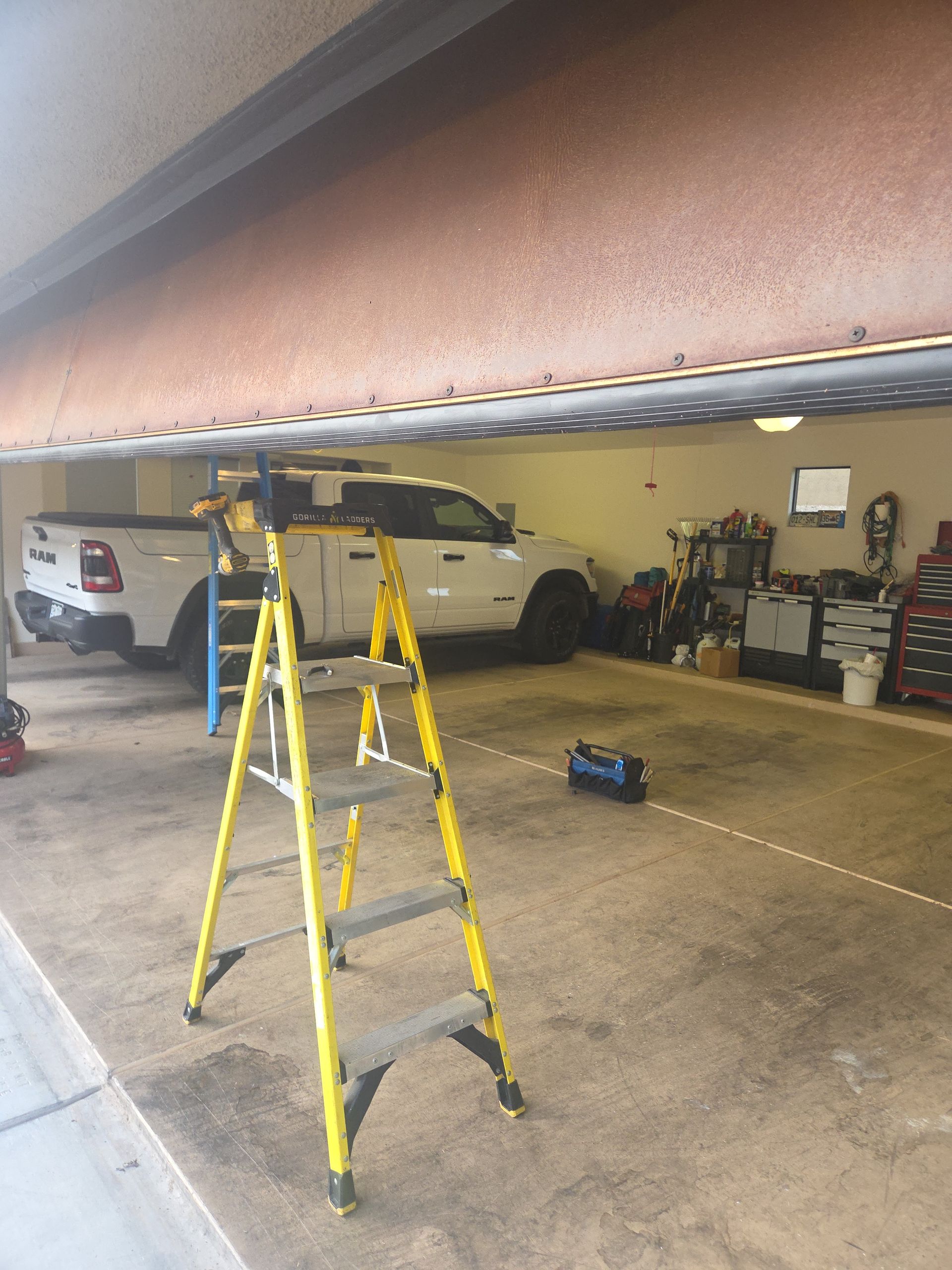 A man is using a drill to install a garage door.