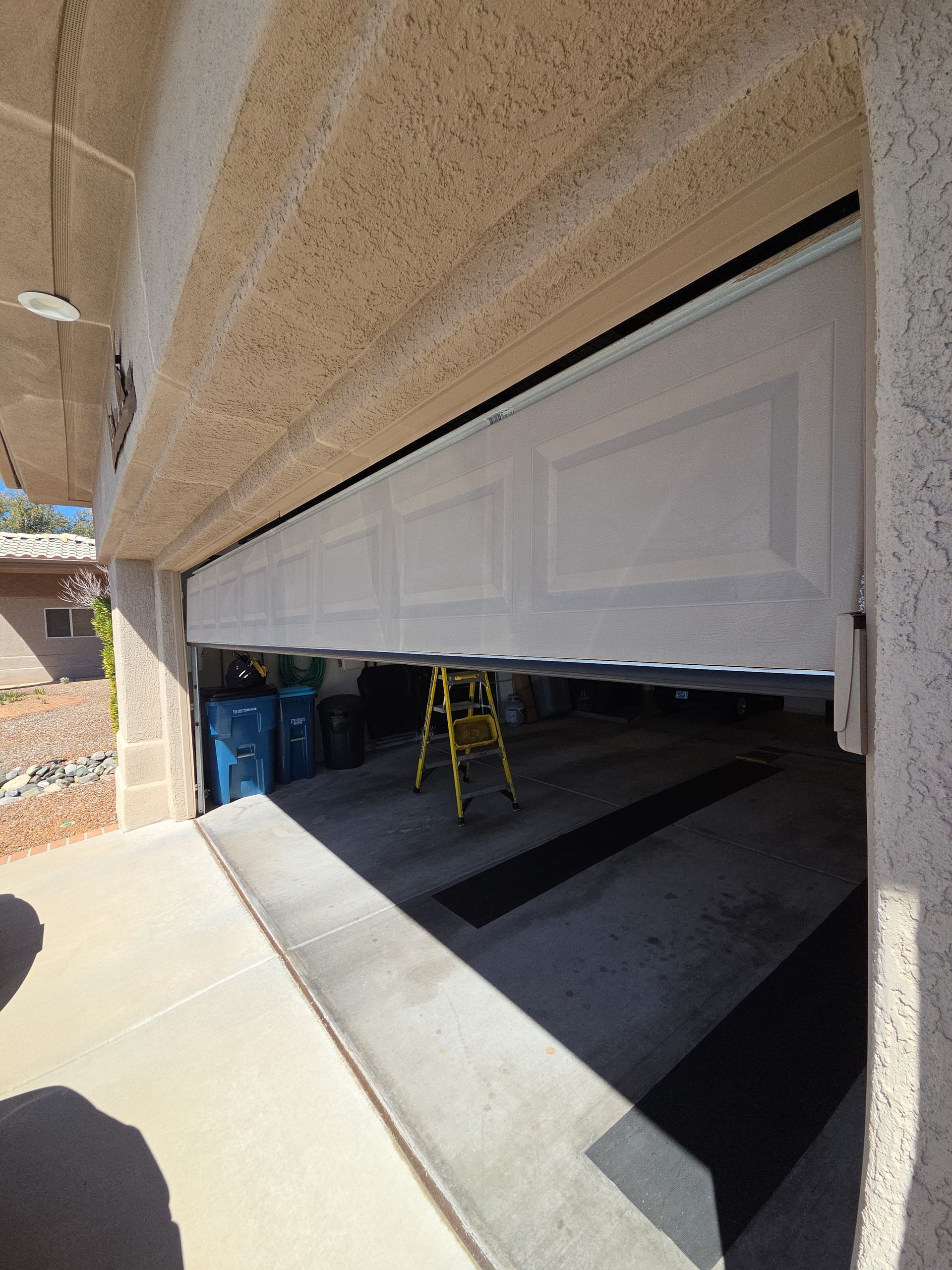 A white van is parked in a garage with a garage door open.