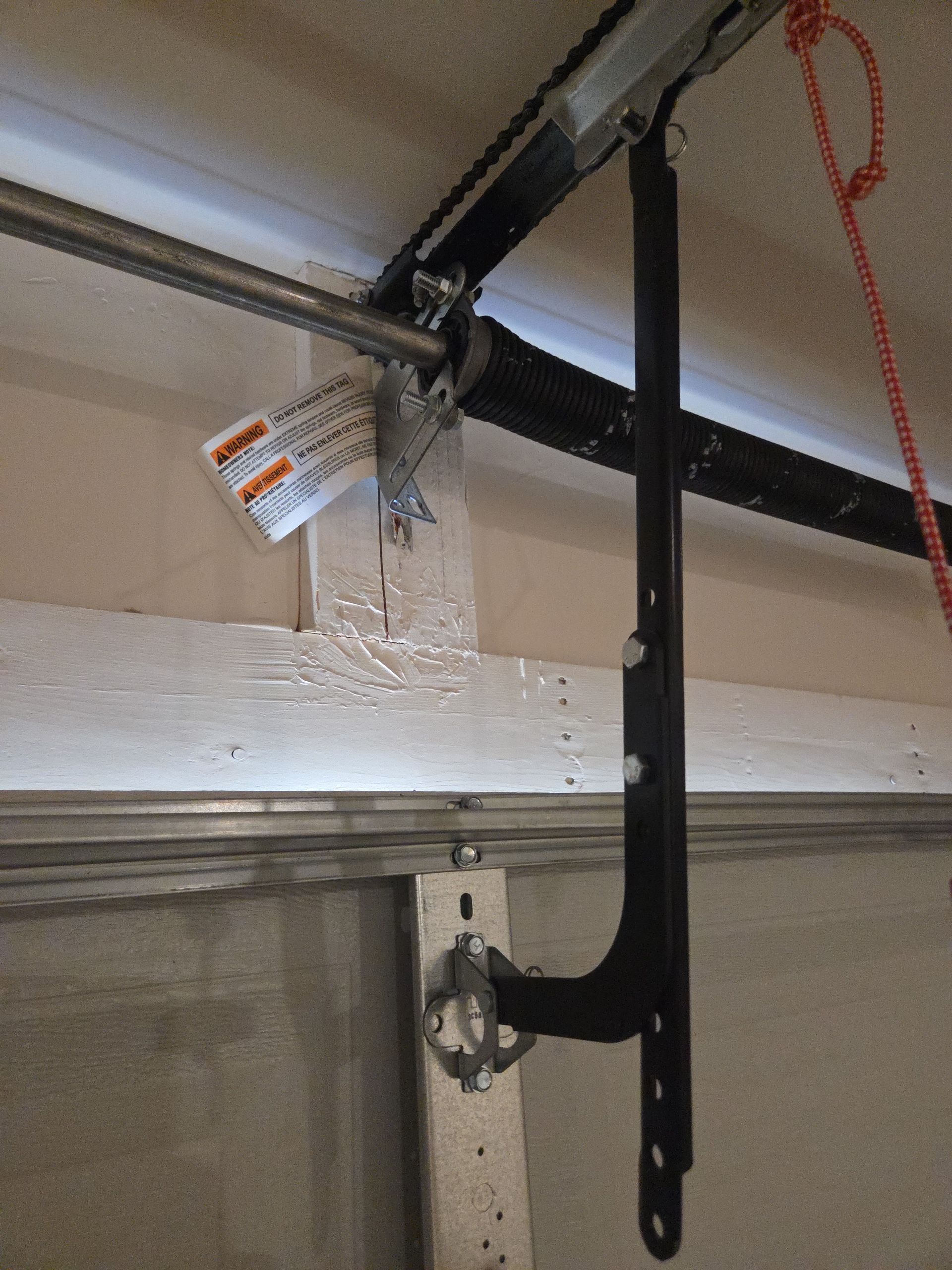 A man is using a drill to install a garage door.