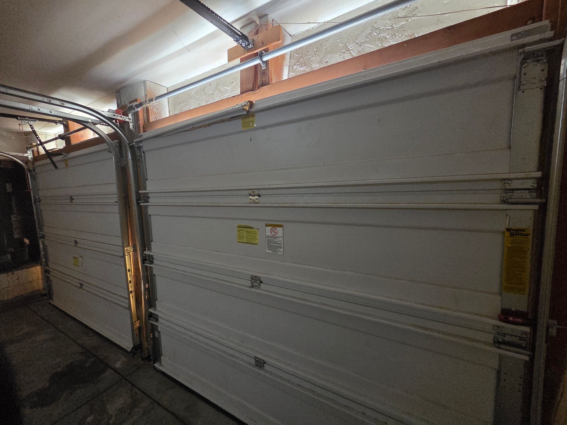 A man is using a drill to install a garage door.
