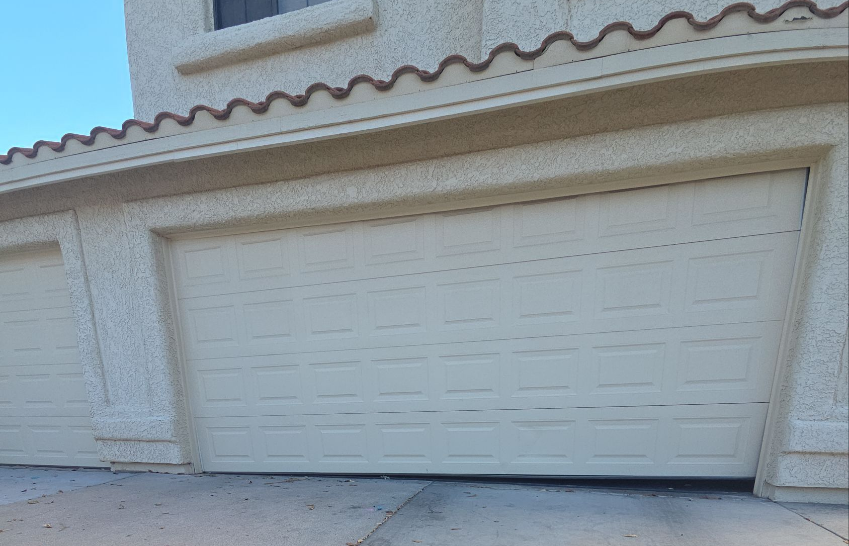 Gray garage door with window panels and stone accent.
