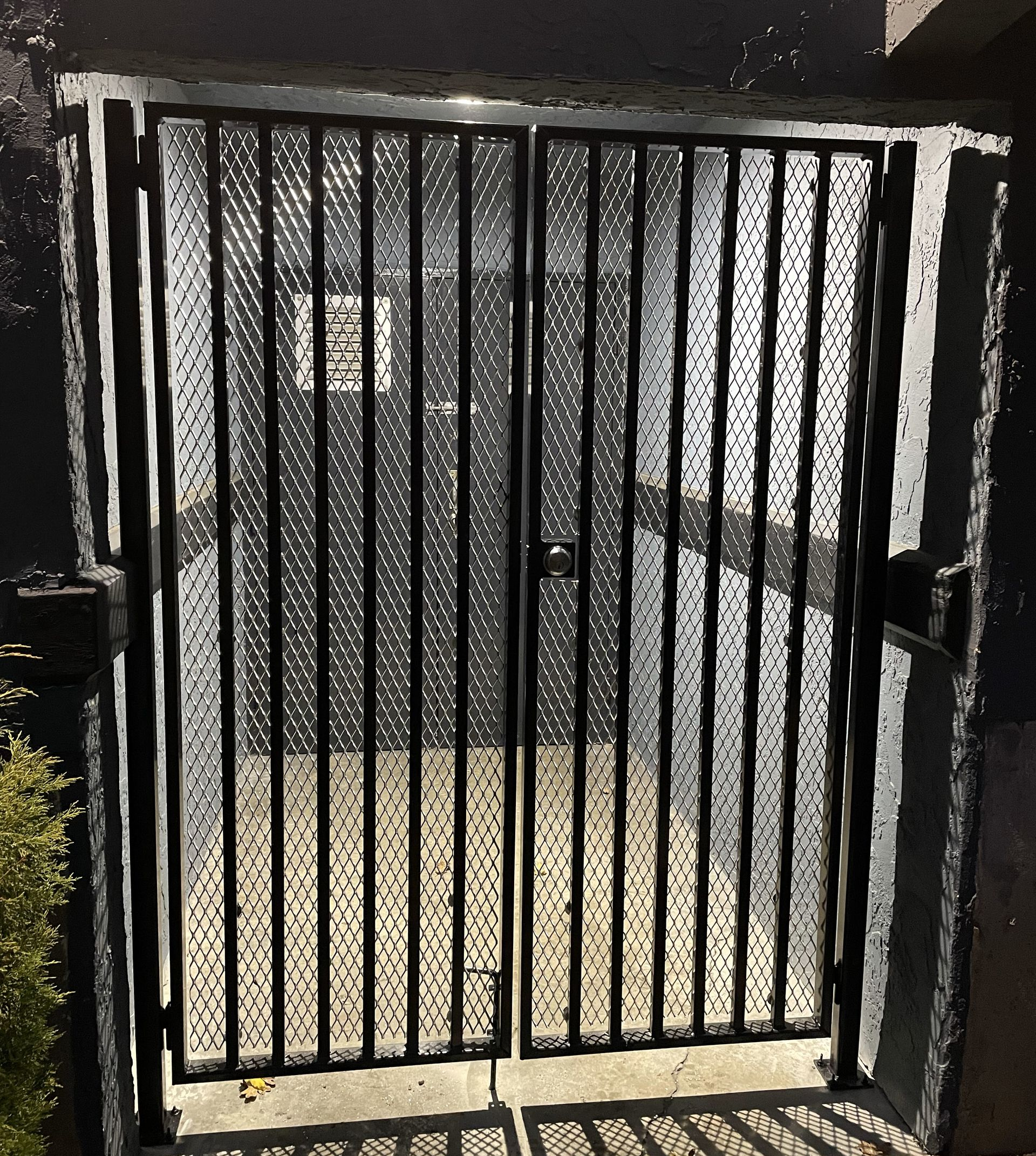 black 2 panel man gate outside a door to a building