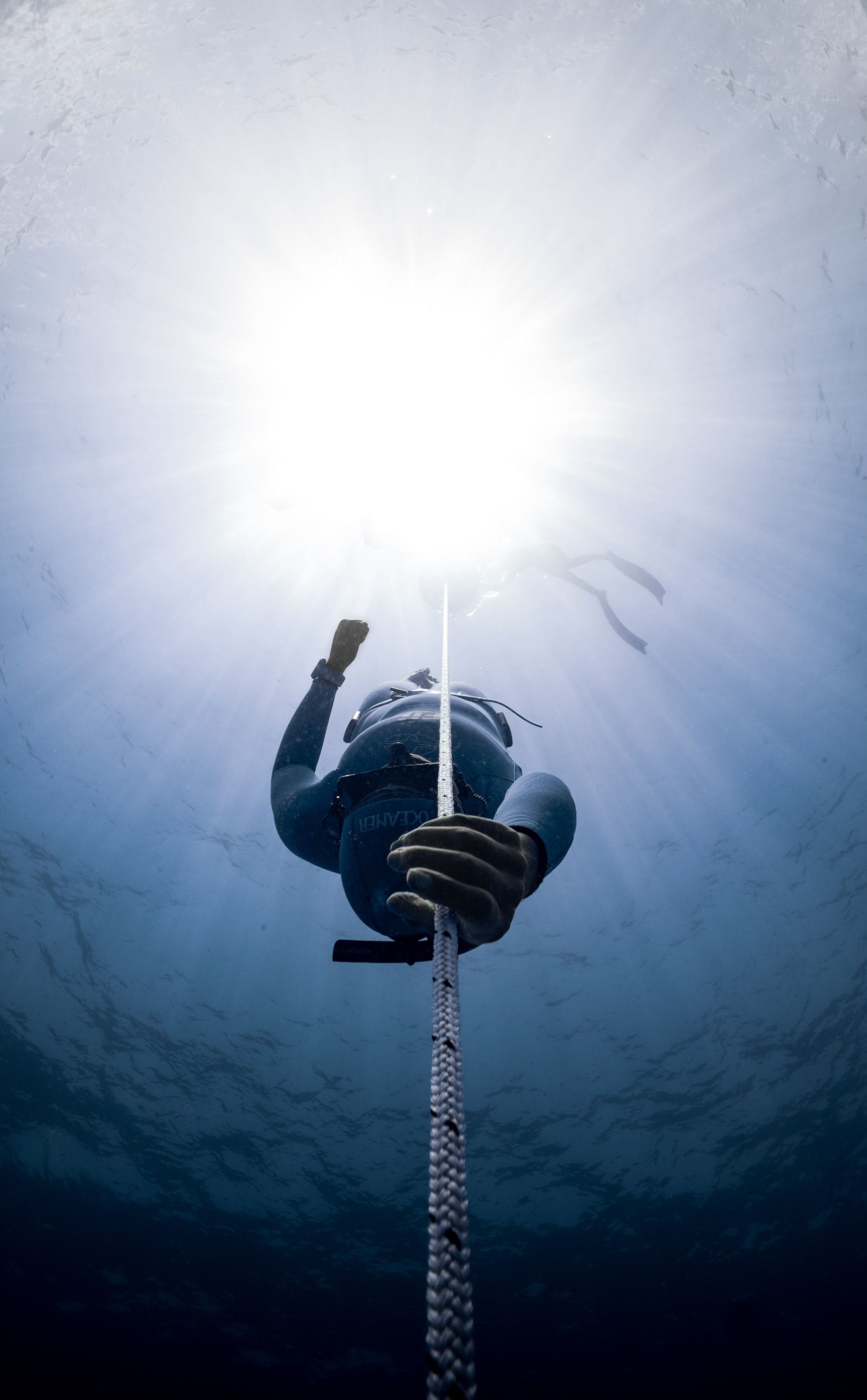 A freedriver going down in the water holding a rope.
