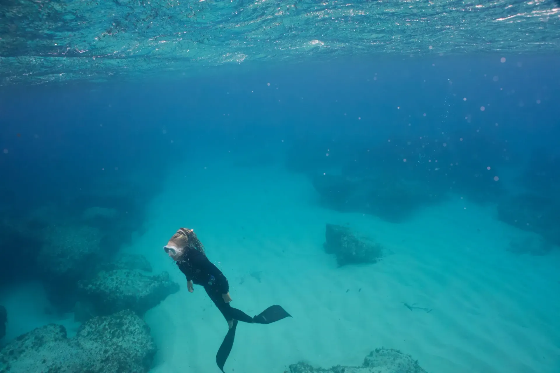 A person is freediving in the ocean near a coral reef.