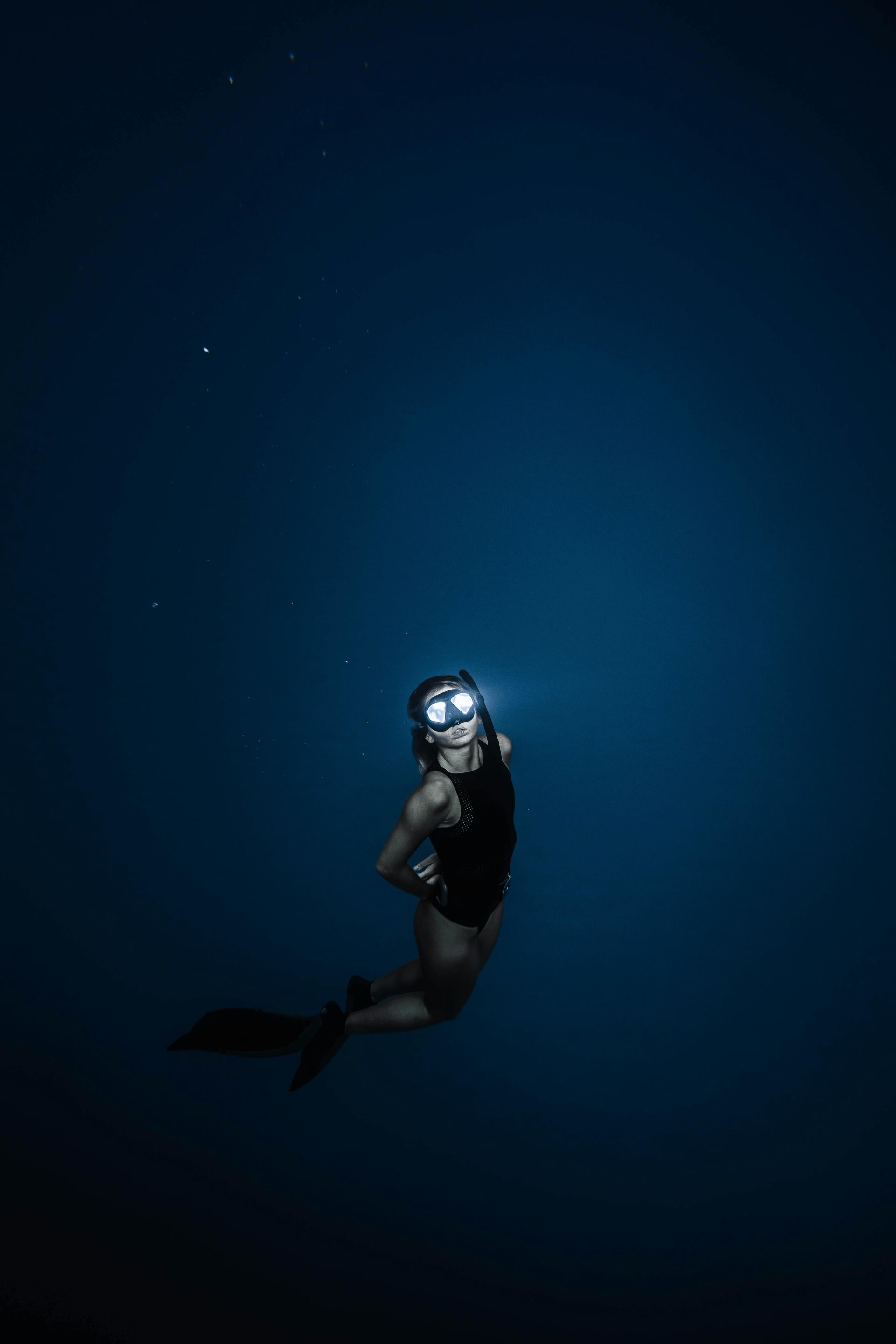 A freediver is swimming in the ocean at night.