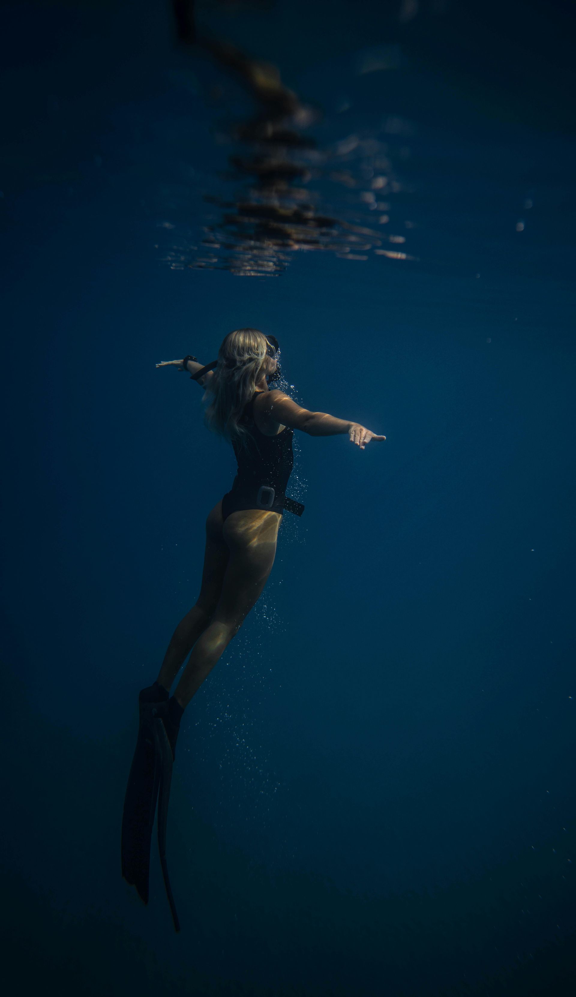 A woman is sfreediving underwater in the ocean.