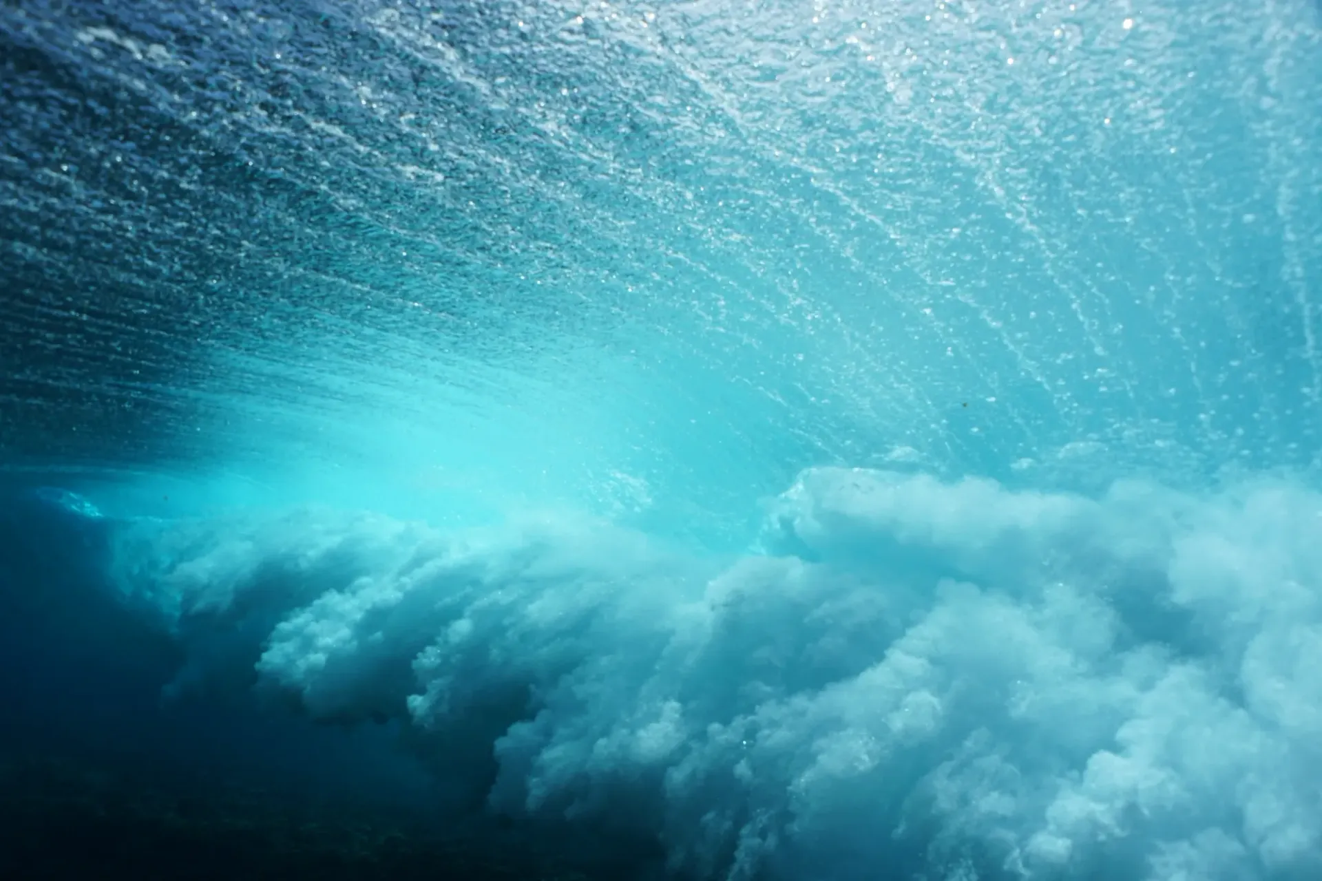 A wave is breaking in the ocean underwater.
