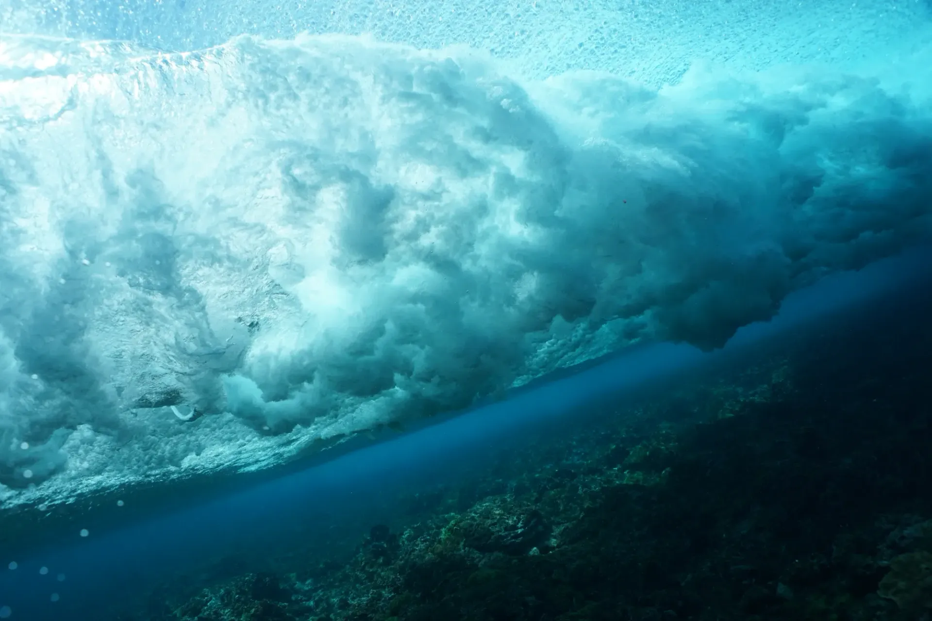 A wave is crashing on a coral reef in the ocean.