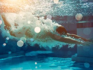 A man is swimming underwater in a swimming pool.