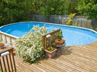 A large swimming pool is sitting on top of a wooden deck.