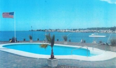 An american flag is flying over a large swimming pool.