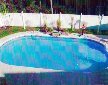 A large swimming pool with a white fence surrounding it