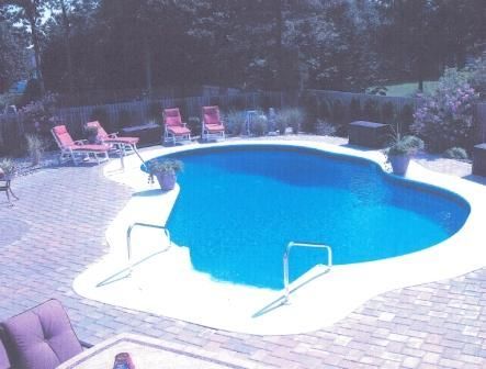 A large swimming pool surrounded by chairs and a table