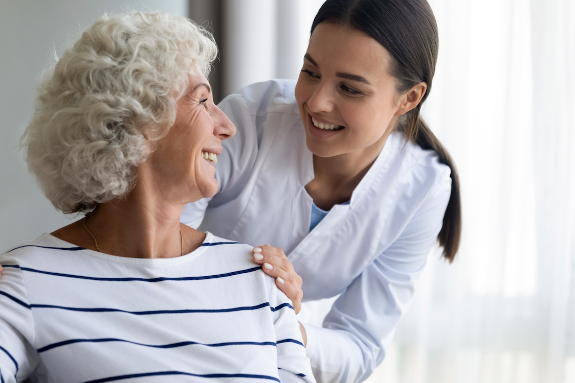 A nurse is talking to an elderly woman in a wheelchair.