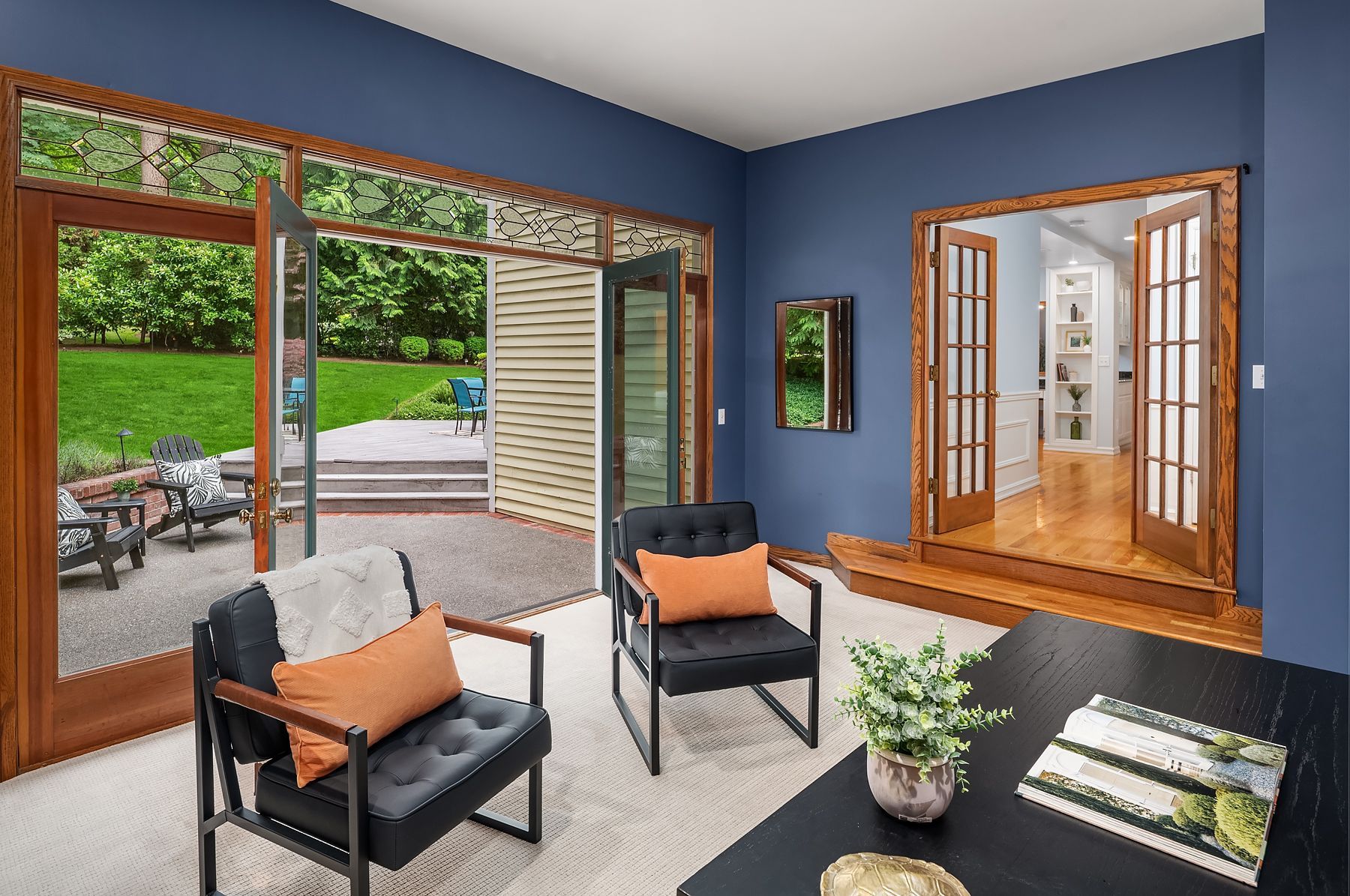 A living room with blue walls , two chairs , a table , and a patio.