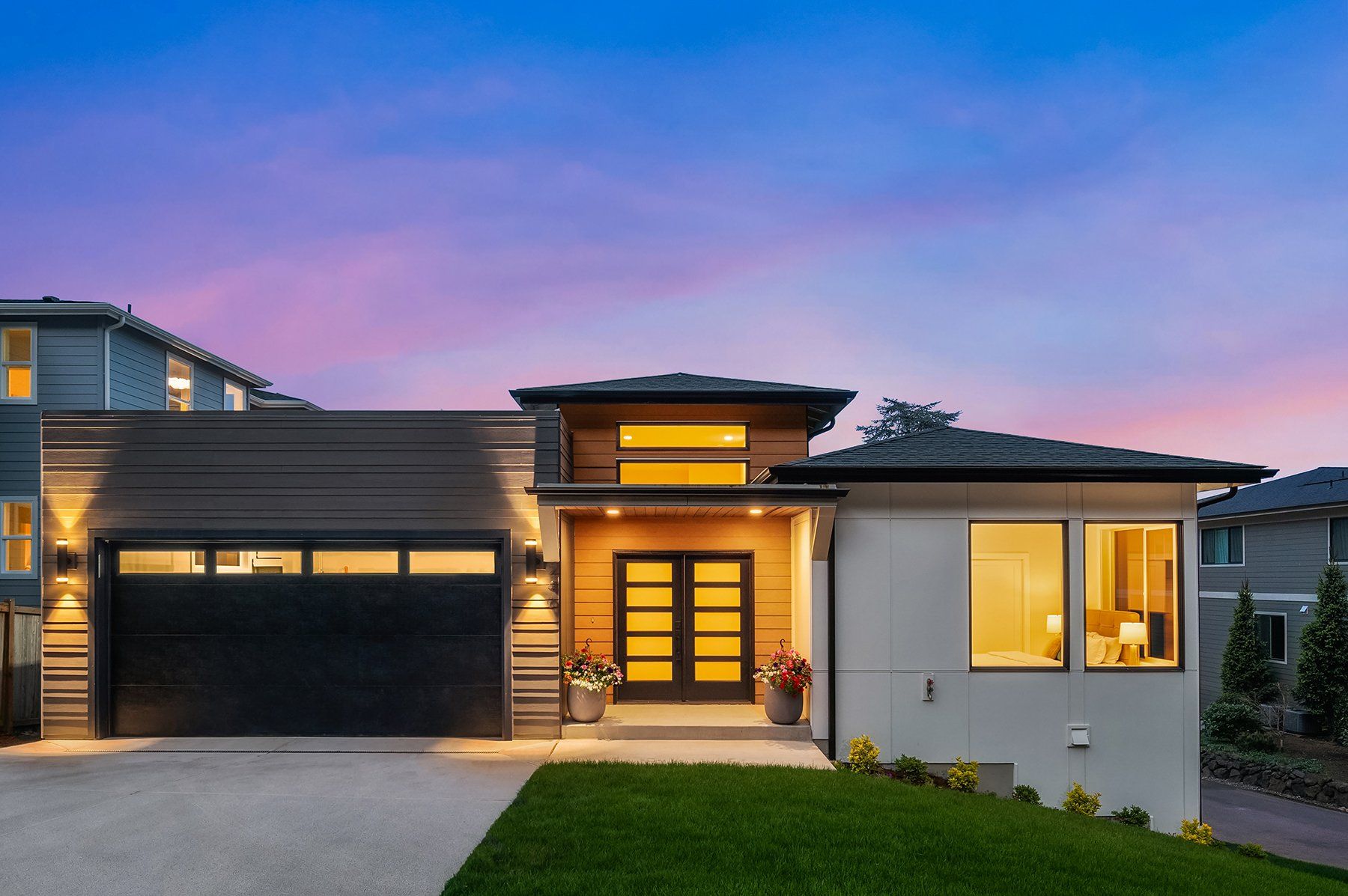 A modern house with a large garage and a lush green lawn.