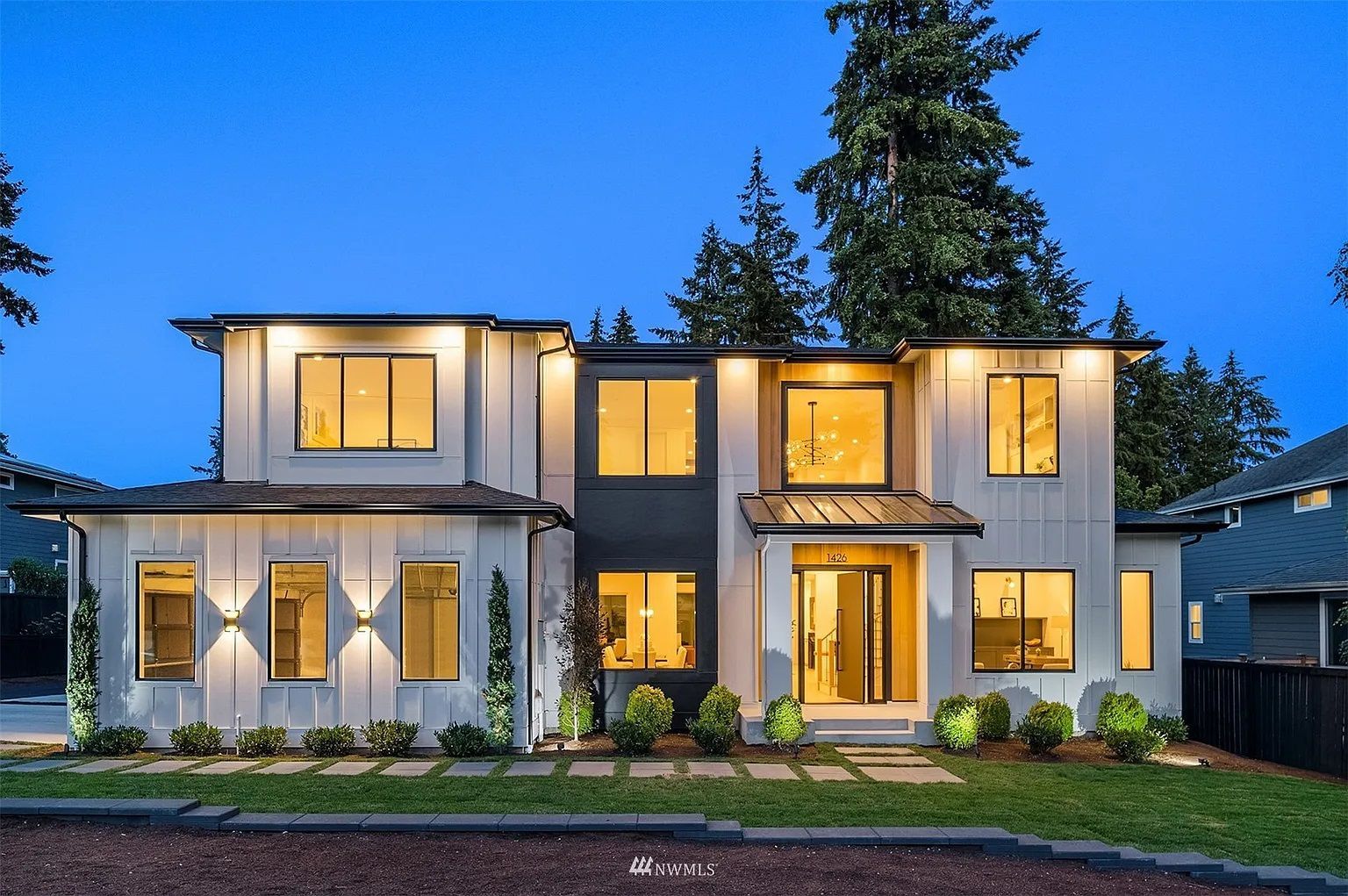 A large house with a lot of windows is lit up at night.