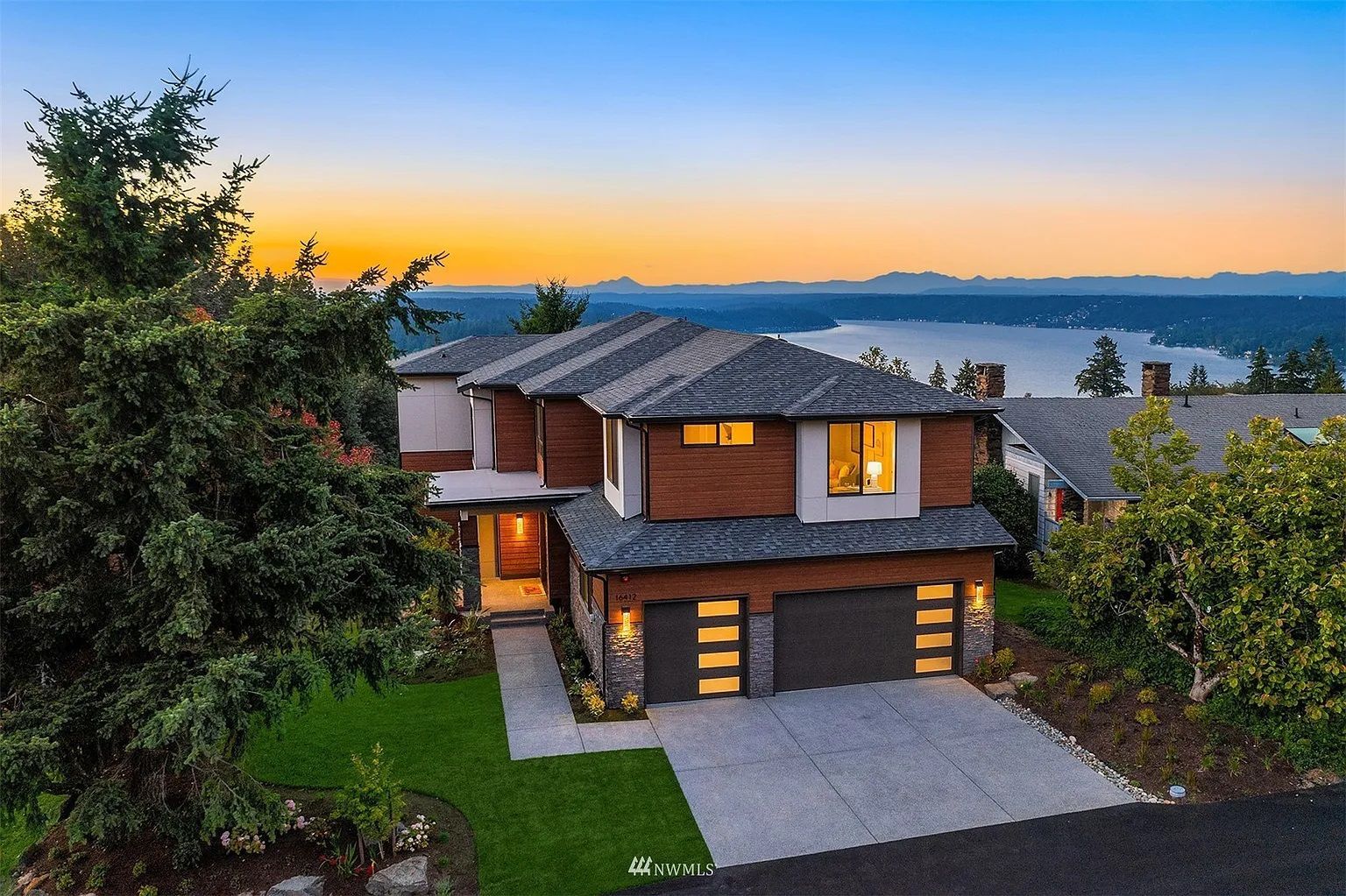 An aerial view of a large house with a view of a lake at sunset.
