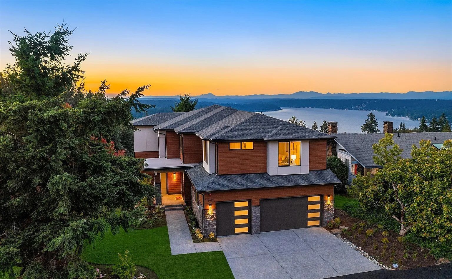 An aerial view of a house with a view of a lake at sunset.