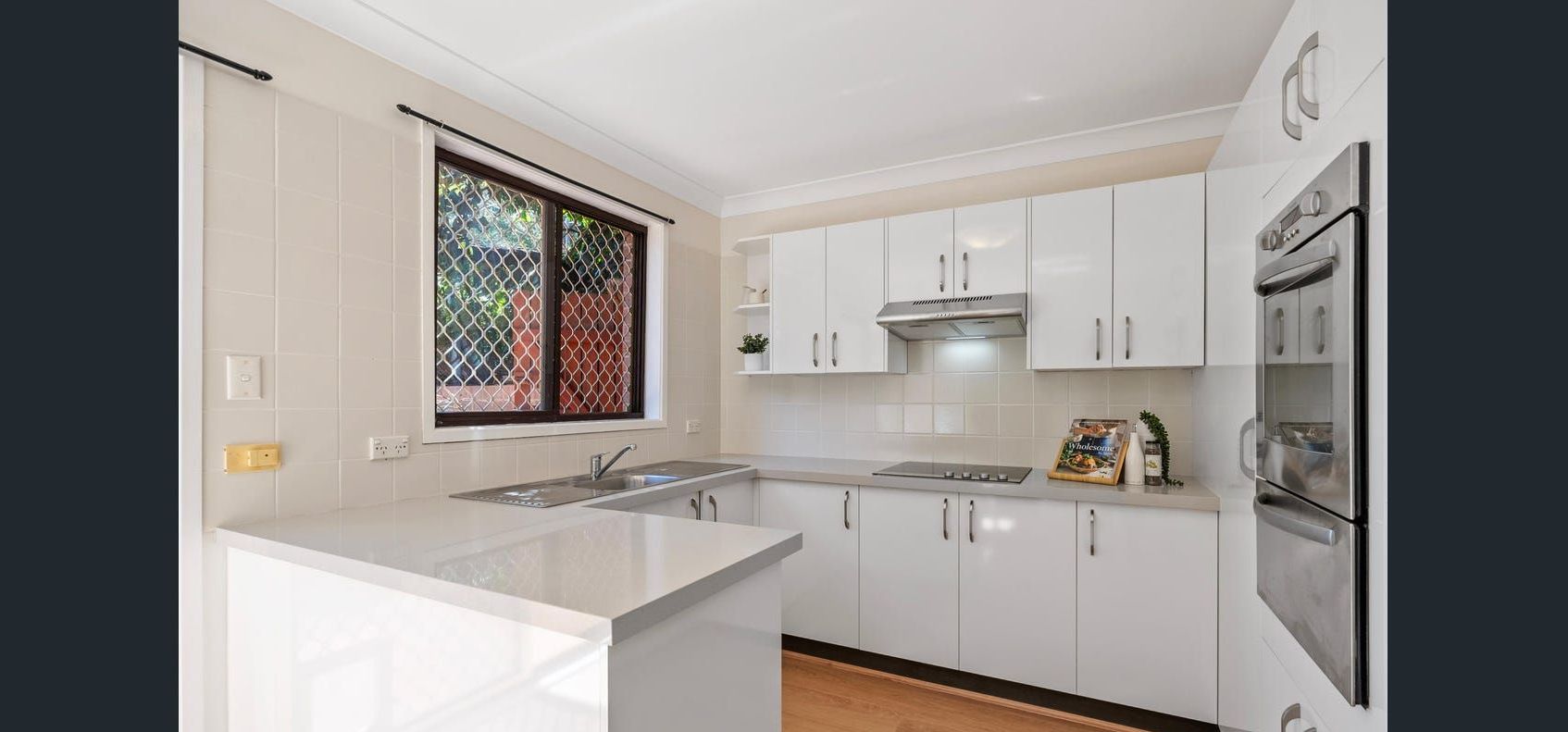 A Kitchen With Stainless Steel Appliances And Wooden Cabinets — Wards Kitchens in Berkeley Vale, NSW