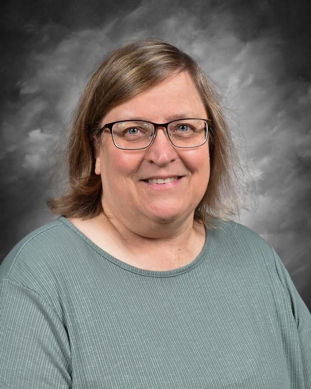 A woman wearing glasses and a sweater is posing for a picture.