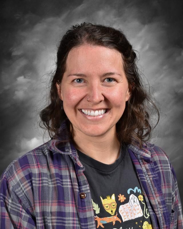 A woman in a maroon shirt is smiling in front of a blue background.